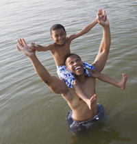 Son sitting on father's shoulders in a lake